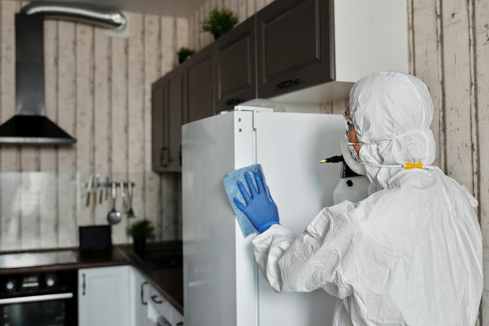 Protective-suit worker disinfecting a kitchen area